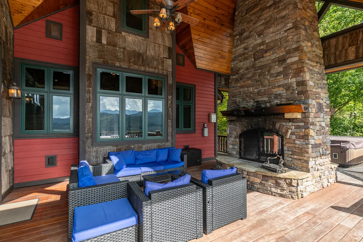 An inviting exterior lounge area features a large stone fireplace, comfortable blue seating, and a wooden ceiling, perfect for group socializing, stargazing, or relaxing after a day’s adventure.