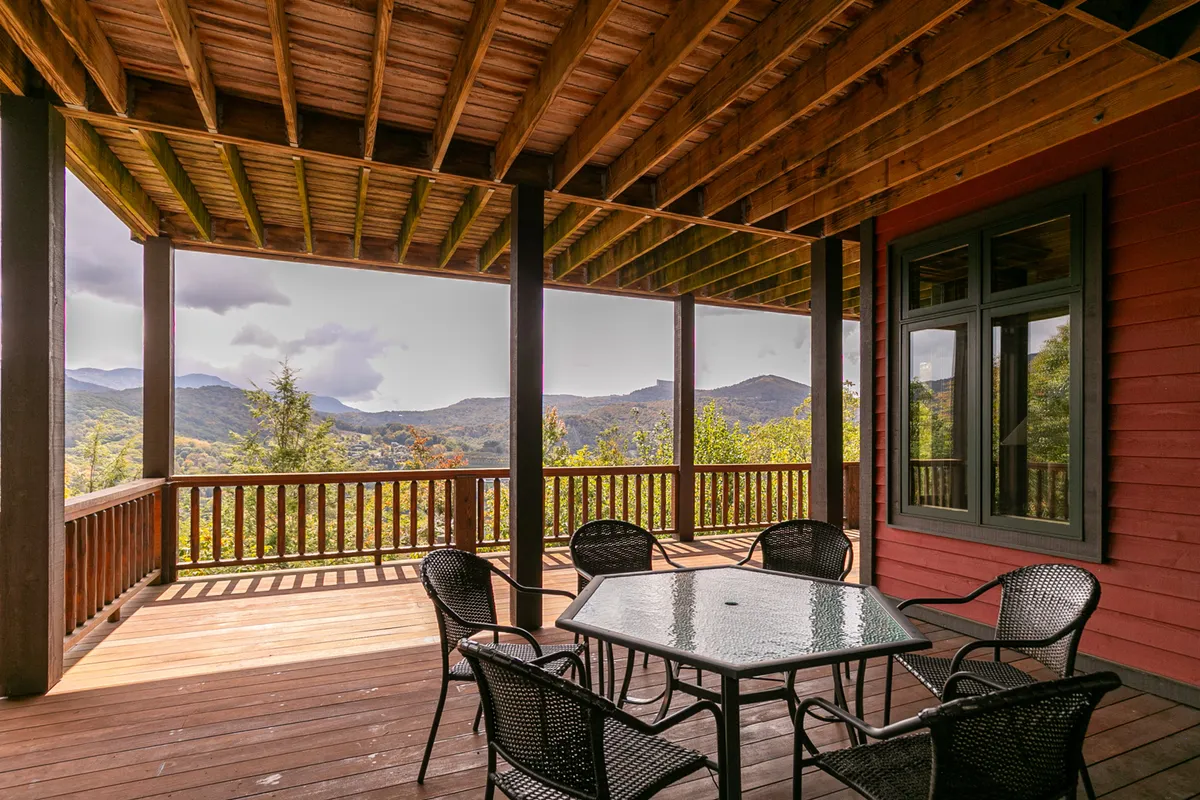 An inviting outdoor table and chair set positioned on a deck overlooking a sweeping mountain vista. The setting is tranquil, suggesting opportunities for morning coffee, casual meals, or evening relaxation while enjoying the changing light and seasons.