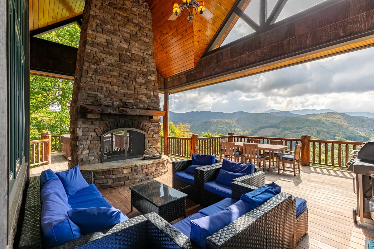 A cozy outdoor seating area centered on a grand stone fireplace, with a sweeping mountain view as the backdrop. The space is ideal for social gatherings, outdoor dining, or unwinding after a day of team-building activities.