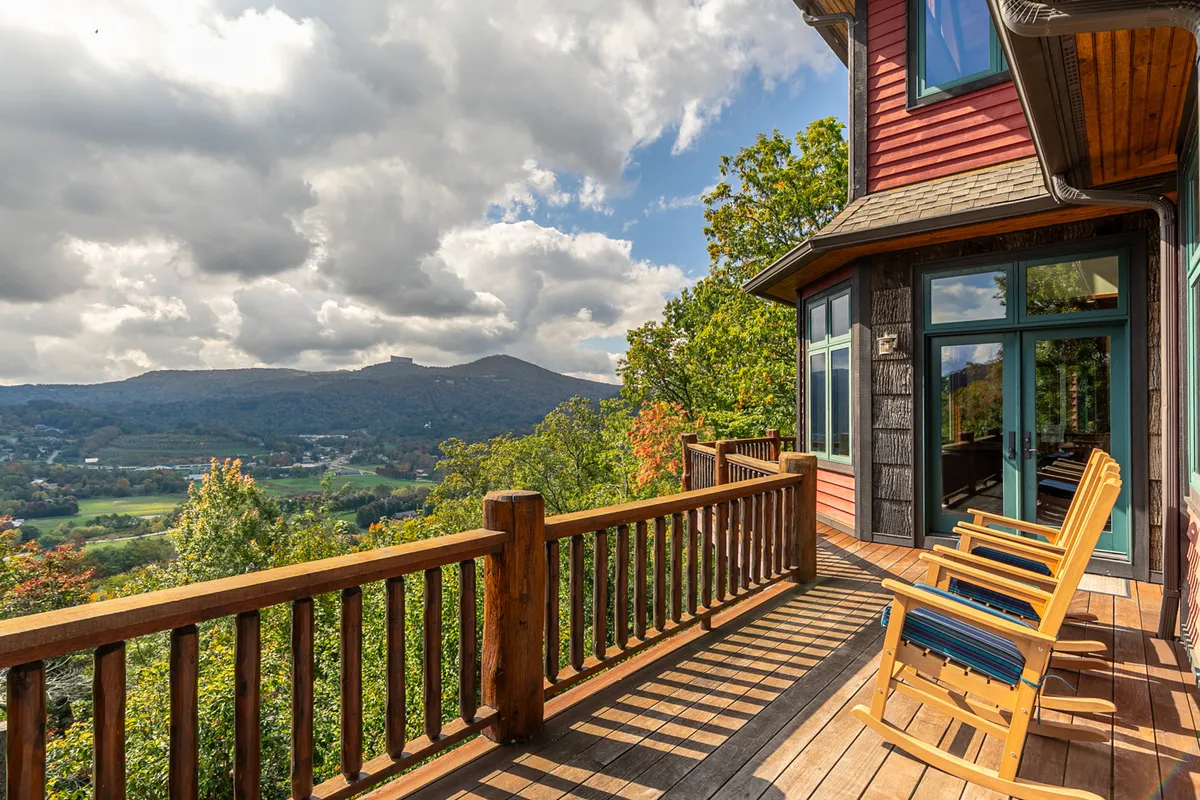 A peaceful deck scene with classic wooden rocking chairs overlooking a panoramic mountain vista, inviting guests to relax, stargaze, or enjoy the quiet beauty of the mountains.