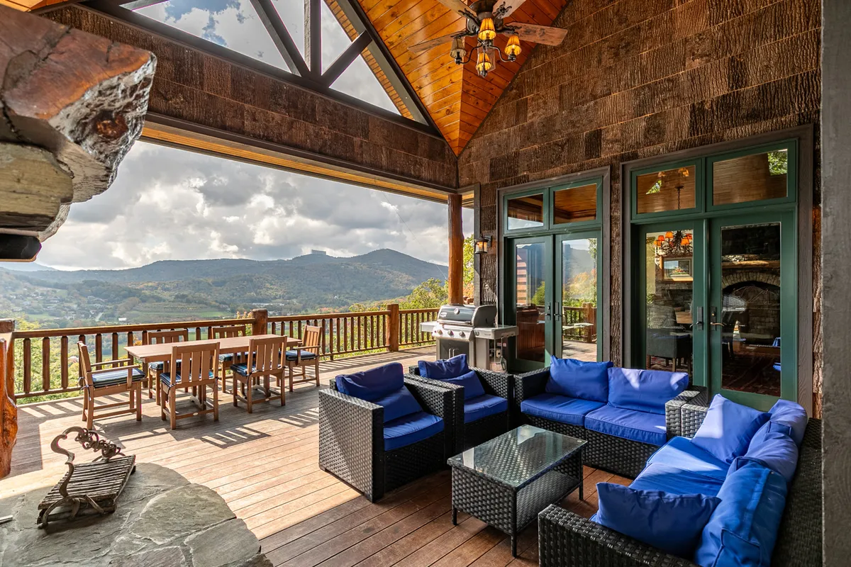 A beautifully arranged outdoor living space with lounge seating, a dining table, a grill, and panoramic mountain views. It's set up for outdoor dining and family gatherings against a stunning natural backdrop.